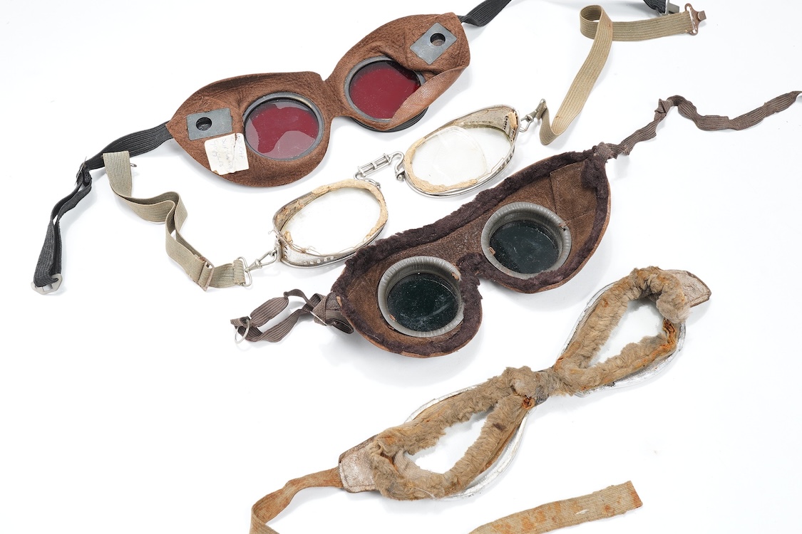 A pair of early aviation aluminium framed flying goggles, a pair of leather and felt lined goggles with green tinted lenses, a pair of French ? aviator flying goggles and a pair of WW2 First Pattern RAF Night Simulation